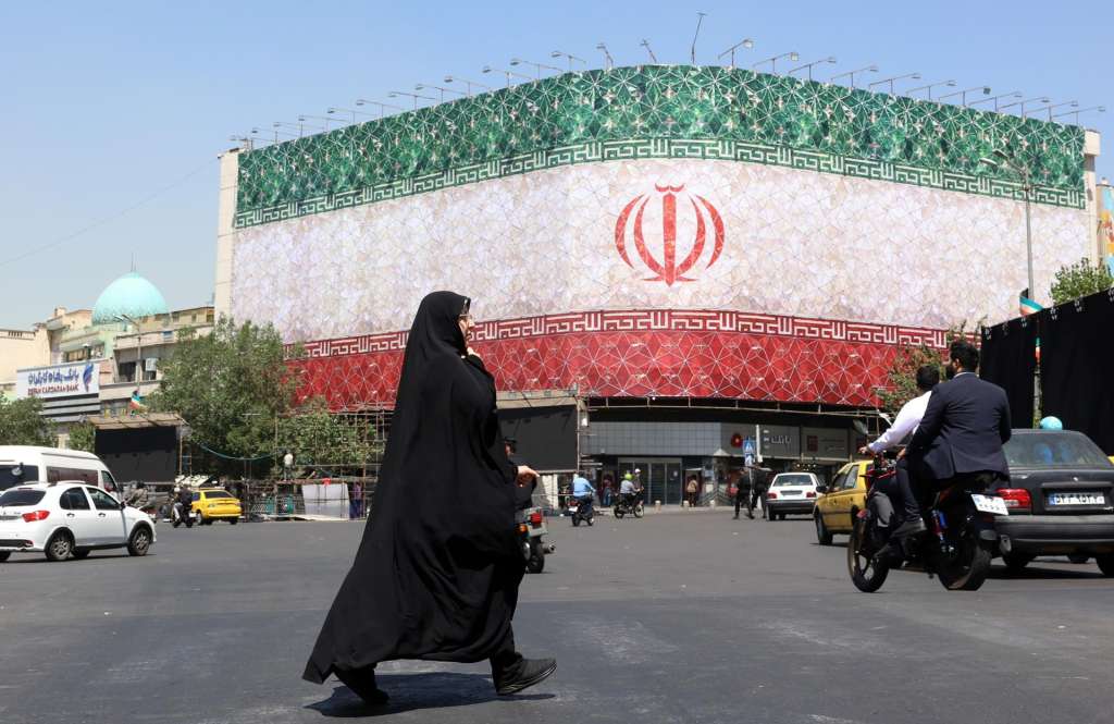 TEHRAN (IRAN(Islamic Republic Of)), 14/06/2026.- A veiled Iranian woman walks past a billboard featuring Iran's national flag at Enqelab Square in Tehran, Iran, 14 June 2026. US President Donald Trump saying on a social media platform that a deal could be signed soon. (Teherán) EFE/EPA/ABEDIN TAHERKENAREH RESTRICTIONS: NO Access Israel Media/Persian Language TV Stations Outside Iran/Strictly No Access BBC Persian/VOA Persian/Manoto TV/Iran International TV. (As mandated by Iran's Directorate General for Foreign Media) --