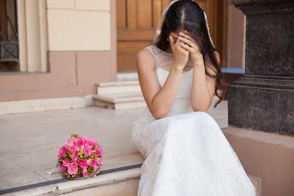 Una novia desolada, con su vertido de gala, llora sentada por la ausencia de su prometido.