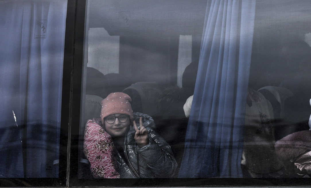 Una niña hace el signo de la victoria desde un autobús en el que ha llegado a Zaporiyia. Esta ciudad del centro este de Ucrania se ha convertido en el lugar al que llegan la mayor parte de personas que huyen de Mariúpol y las localidades cercanas controladas por el ejercito ruso.