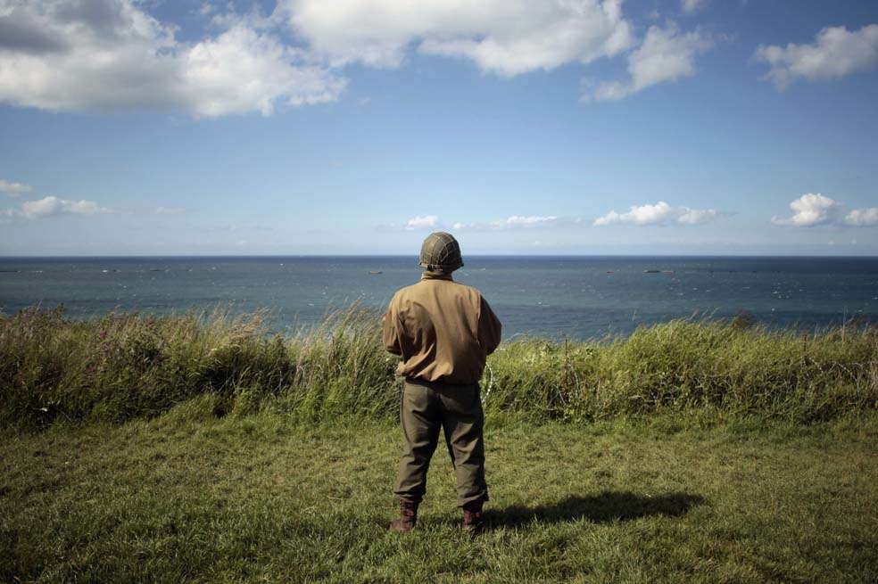 Un hombre con el uniforme del ejército de Estados Unidos durante la Segunda Guerra Mundial mira al mar en la costa norte francesa. / Fotos: AFP