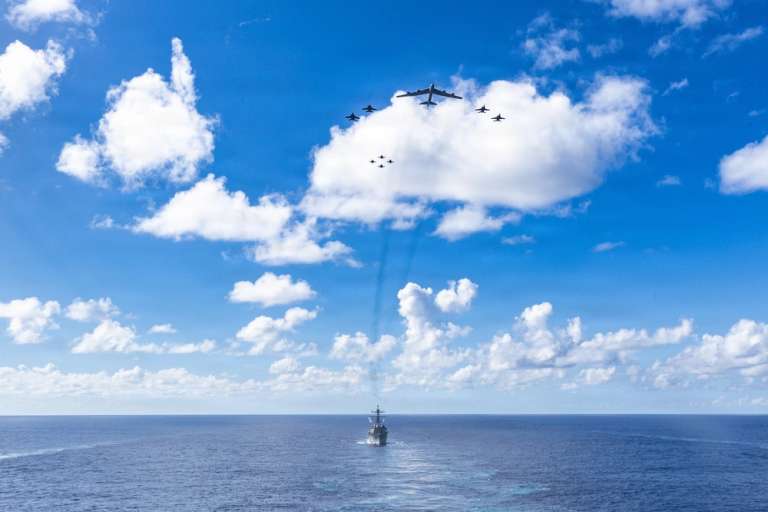 En el agua, uno de los destructores de misiles que escoltan al USS Gerald Ford; en el cielo, unidades del portaaviones y el bombardero B-52.