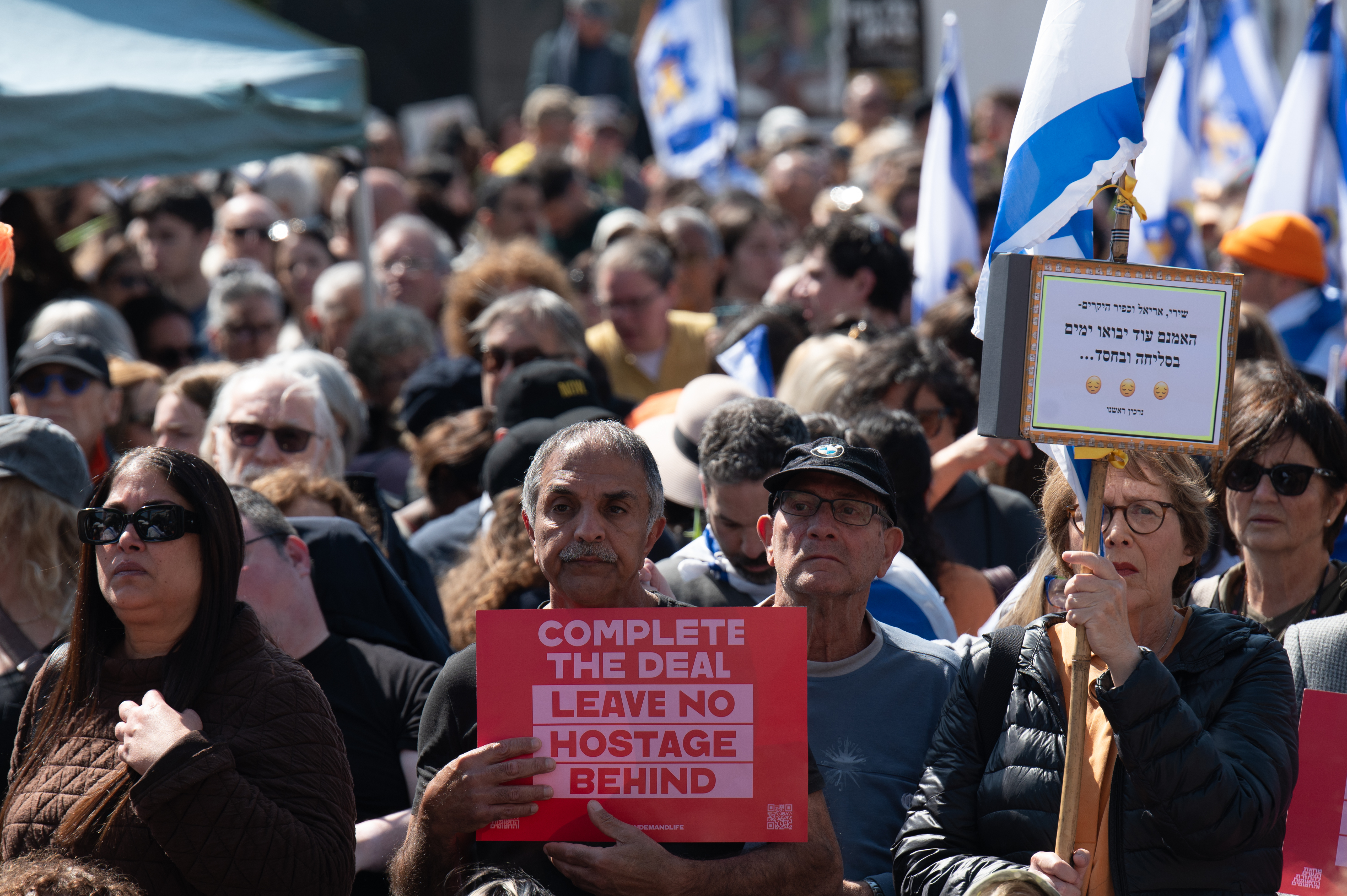 JERUSALÉN, 26/02/2025.- Plaza de los secuestrados en Tel Aviv, donde decenas de ciudadanos acudieron para visualizar en una pantalla el entierro de Shiri Bibas y sus dos hijos Ariel y Kfir. Miles de personas salieron a las calles de Israel con banderas y pancartas para seguir la marcha fúnebre de los exrehenes Shiri Bibas y sus dos hijos, Ariel y Kfir, camino de la frontera con la Franja de Gaza, donde serán enterrados. En imágenes compartidas por grupos prodemocracia israelíes (que se han sumado a las manifestaciones semanales de las familias de los rehenes para pedir un acuerdo de alto el fuego en Gaza) se puede ver a grandes multitudes esperando junto a la carretera, ondeando banderas israelíes. EFE/ Magda Gibelli