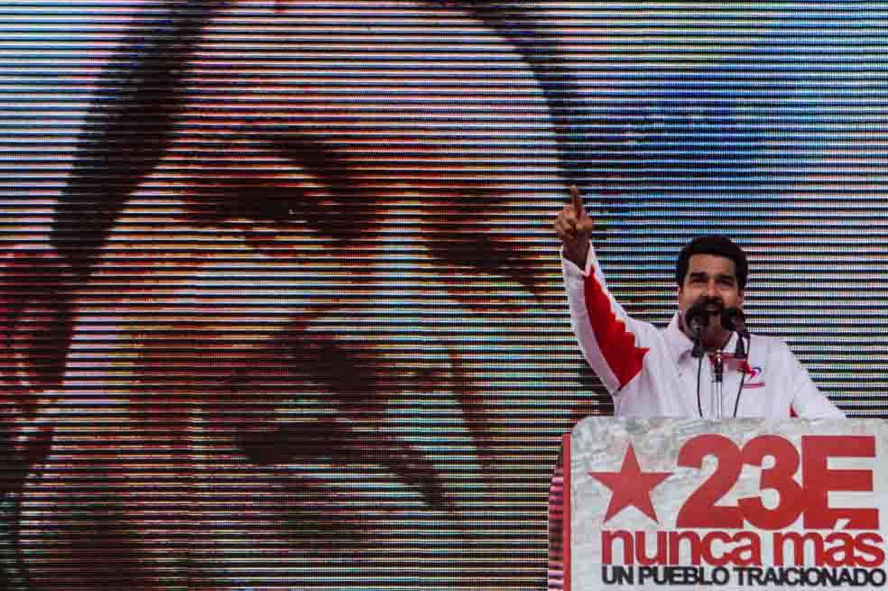 Nicolás Maduro da un discurso, mientras a su espalda se proyecta una imagen de Hugo Chávez. / EFE