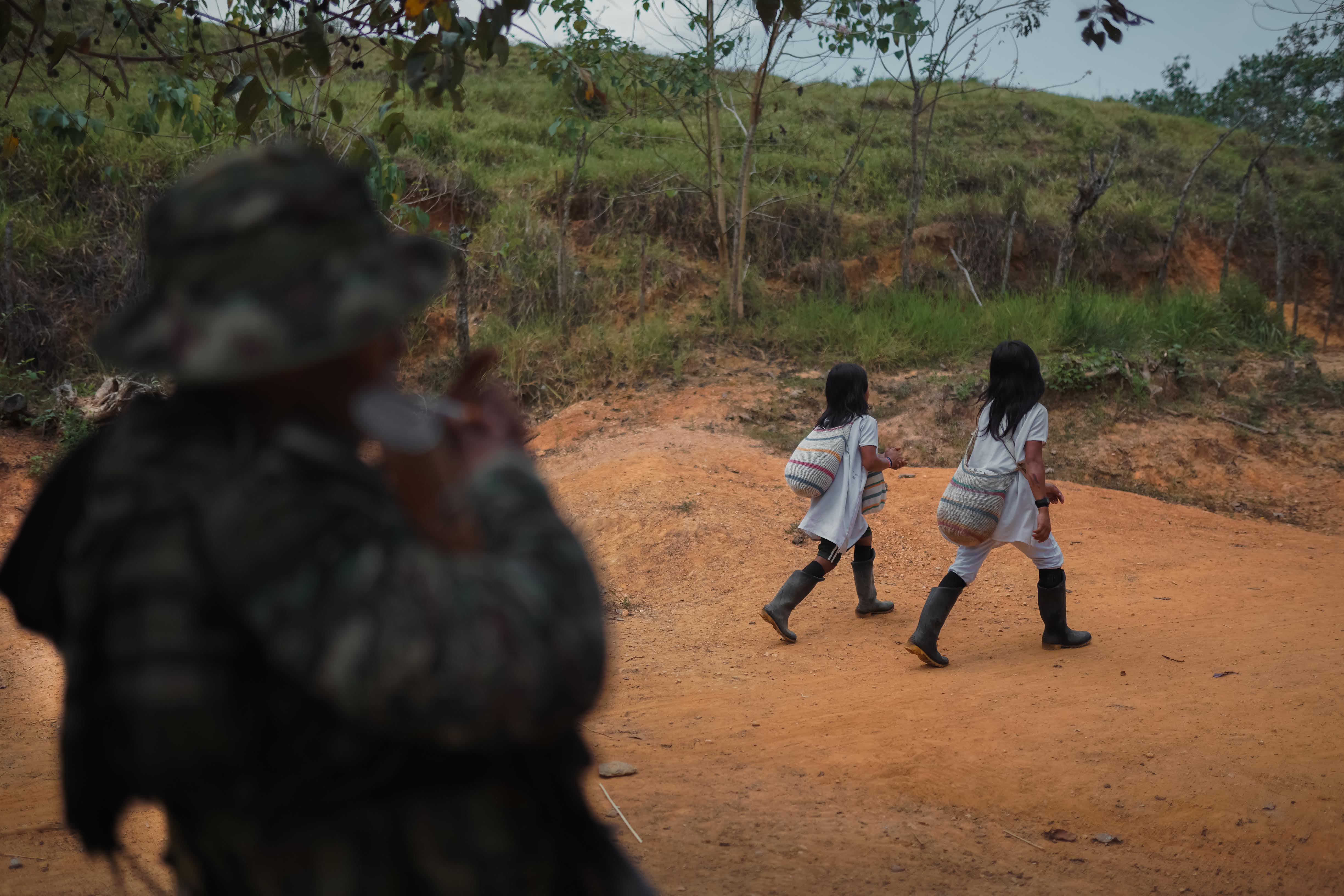 Dos niños del pueblo indígena Wiwa caminan frente a un combatiente de las Autodefensas Conquistadoras, en una vereda de la Sierra Nevada de Santa Marta.