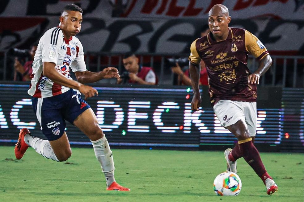 Junior Hernández, del Tolima, conduce el balón ante la marca de Jordan Barrera, volante del Junior.