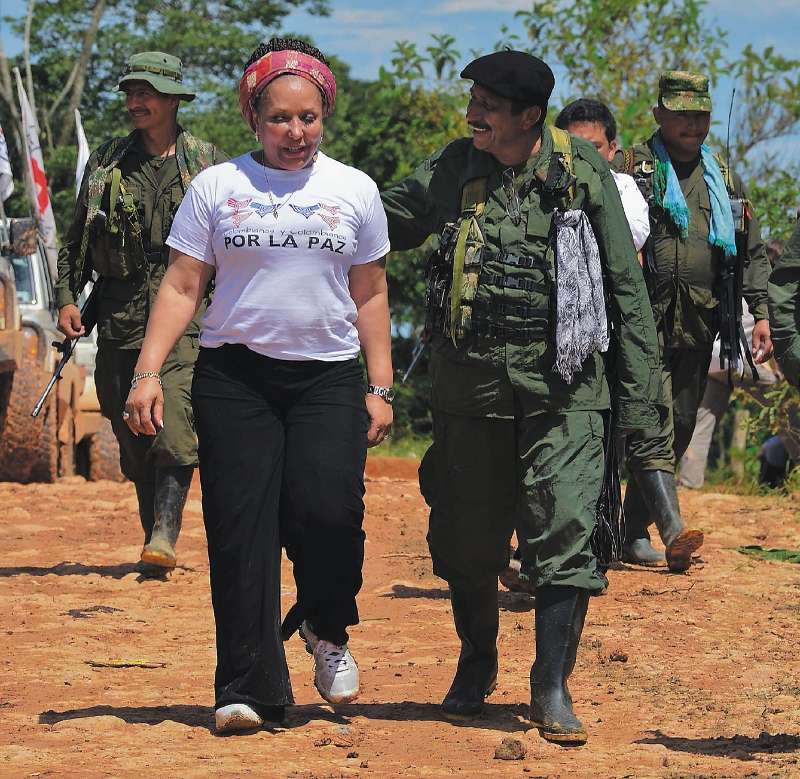 Revolutionary Armed Forces of Colombia (FARC) guerrilla commander, Jairo (C), walks with Colombian former senator Piedad Cordoba (L) in San Isidro, in the Colombian southern department of Caqueta, on May 30, 2012 as the humanitarian mission waits for the release of French journalist Romeo Langlois, held by the rebels for more than a month. France 24 reporter Romeo Langlois was captured at the end of April by FARC rebels during an attack on a Colombian army unit he was embedded with to film a counter-drug operation.  AFP PHOTO/Luis ACOSTA
