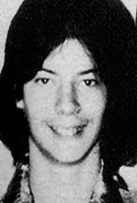 Fotografía en blanco y negro de un hombre joven sonriendo directamente a la cámara.