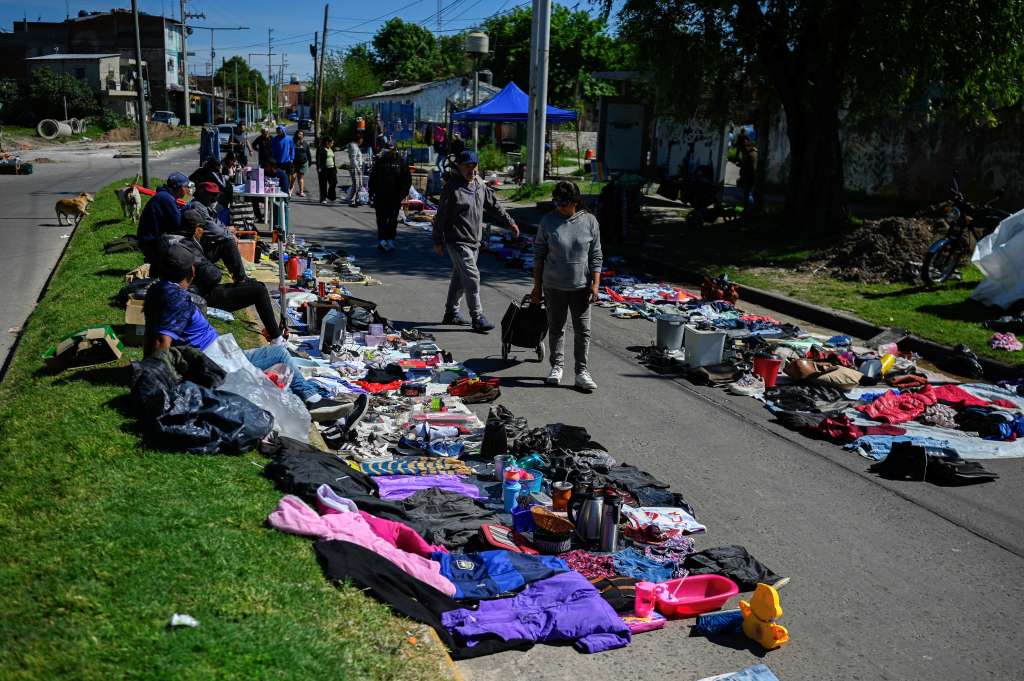 People walk through a street market in Villa Fiorito, on the outskirts of Buenos Aires, on October 19, 2025. The street market in the neighborhood where Diego Maradona was born keeps growing: more and more residents are selling what they have � or what they find on the street � to survive, amid a deepening economic crisis in Argentina on the eve of the elections. (Photo by Luis ROBAYO / AFP)