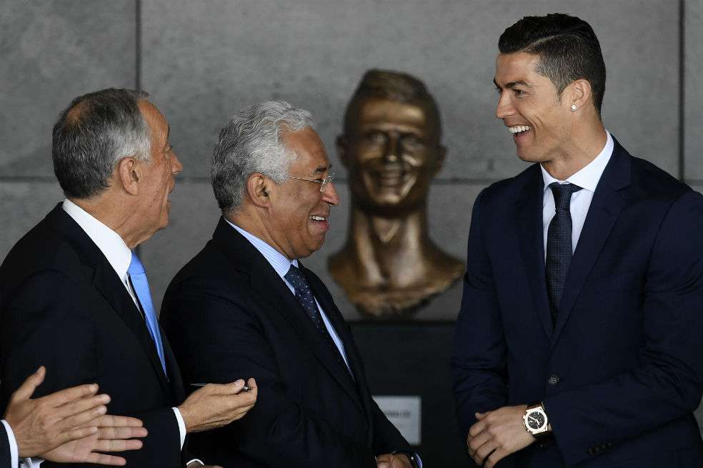 El futbolista portugués (derecha), en compañía del primer ministro Antonio Costa (centro) y el presidente Marcelo Rebelo de Sousa (izquierda) durante la ceremonia en el aeropuerto de Madeira en Funchal. /AFP