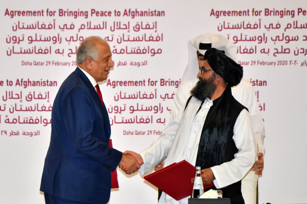 El Representante Especial de Estados Unidos para la Reconciliación de Afganistán, Zalmay Khalilzad, y el cofundador talibán Mullah Abdul Ghani Baradar se dan la mano después de firmar un acuerdo de paz durante una ceremonia en la capital de Qatar, Doha. / AFP