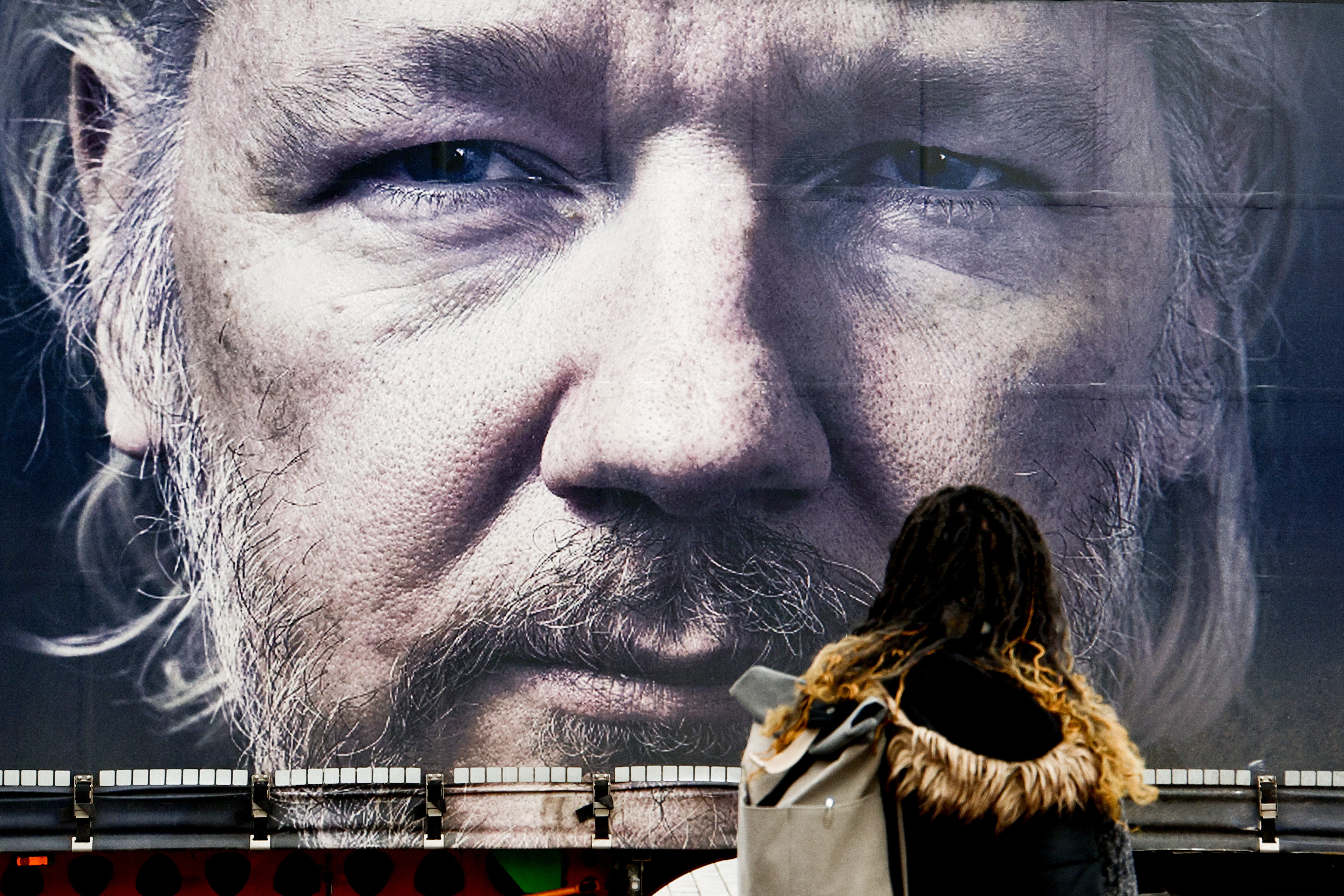 Berlin (Germany), 20/02/2024.- A pedestrian observes truck with giant Assange portrait during a pro-Assange campaigners protest in Berlin, Germany 20 February 2024. Julian Assange is facing his final extradition hearing at the High Court on 20 to 21 February. Assange is facing 175 years in a US prison if the hearing goes against him. (Protestas, Alemania) EFE/EPA/Filip Singer