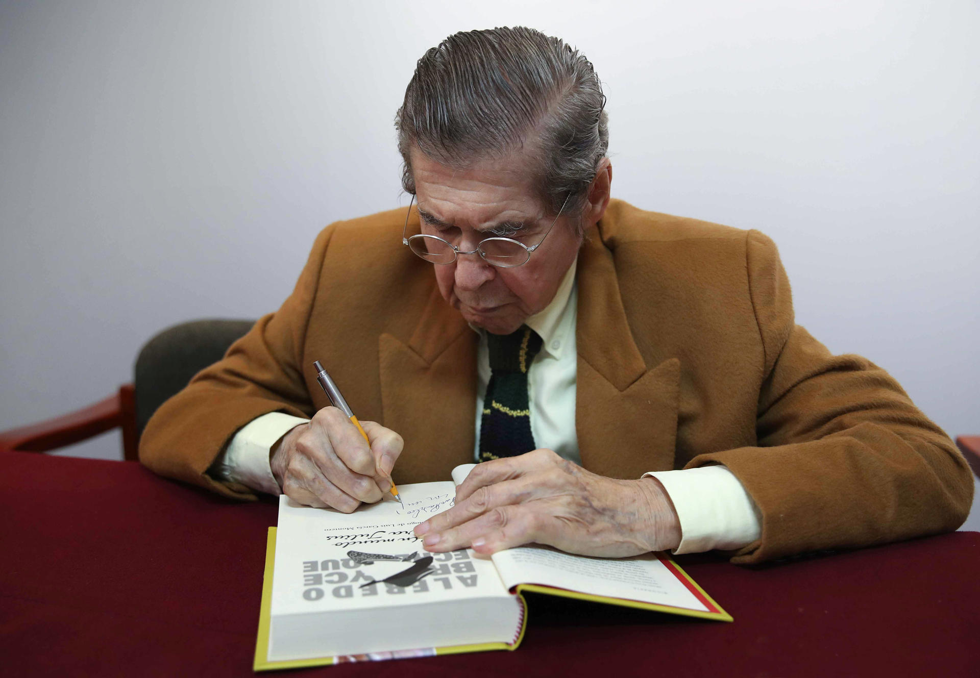 AME8905. LIMA (PERÚ), 13/11/2025.- El célebre escritor peruano Alfredo Bryce Echenique (1939) firma el manuscrito original de su obra 'Un mundo para Julius' durante acto este jueves, en Lima (Perú). Echenique entregó el manuscrito original de su obra 'Un mundo para Julius' a la Caja de las Letras del Instituto Cervantes, como parte del homenaje que celebra esta semana la Universidad Nacional Mayor de San Marcos en Lima. EFE/Paolo Aguilar