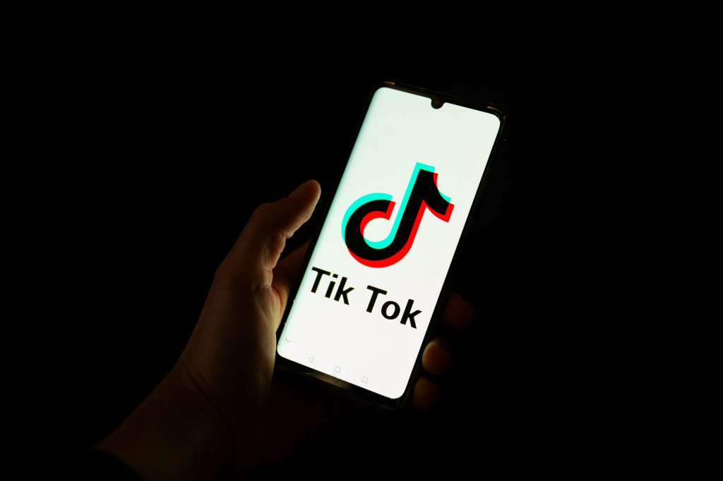 (FILES) This photograph taken on April 19, 2024 shows a man holding a smartphone displaying the logo of Chinese social media platform Tiktok in an office in Paris