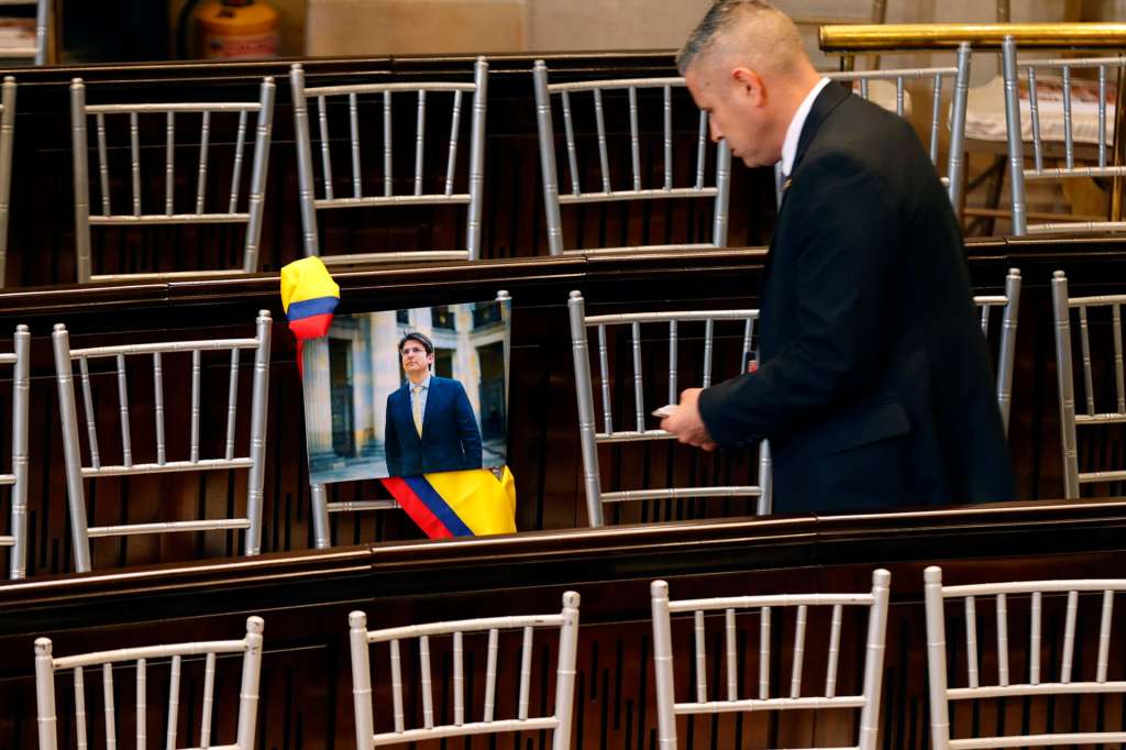 AME4160. BOGOTÁ (COLOMBIA), 20/07/2025.- Una persona observa una fotografía del senador Miguel Uribe puesta en una silla durante la instalación del nuevo periodo de sesiones del Congreso este domingo, en Bogotá (Colombia). Petro destacó ante el Congreso los avances económicos que ha conseguido en sus primeros tres años de Gobierno pero reconoció que no ha logrado sacar adelante la política de "paz total" con los grupos armados, una de sus grandes promesas de campaña. EFE/ Mauricio Dueñas Castañeda