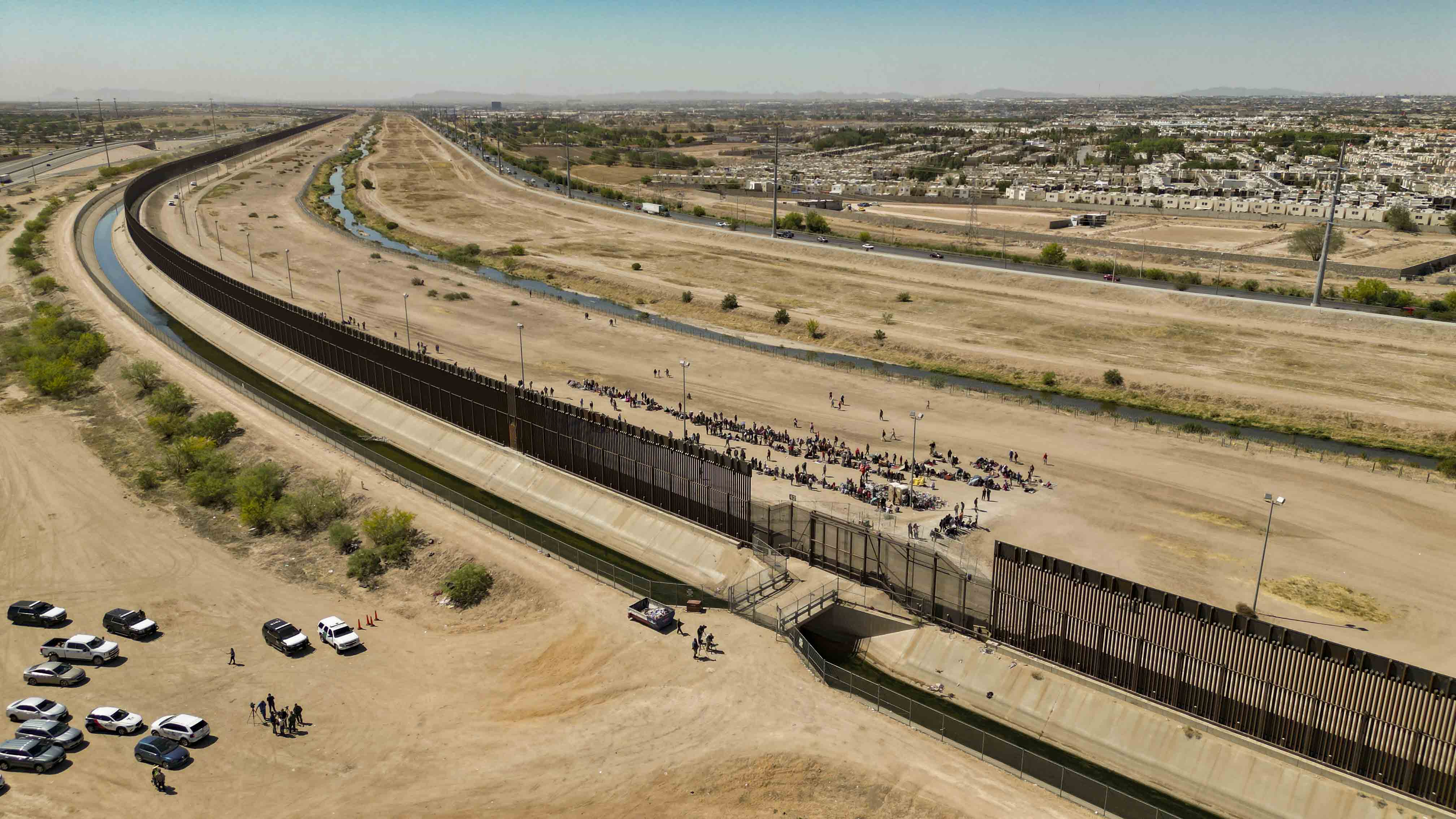 -FOTODELDÍA- AME8333. EL PASO (ESTADOS UNIDOS), 09/05/2023.- Fotografía aérea tomada hoy muestra a cientos de migrantes mientras esperan por papeles junto al muro fronterizo en El Paso, Texas (EE.UU). Varios cientos de migrantes que habían cruzado irregularmente la frontera entre México y Estados Unidos en los últimos días se han entregado este martes voluntariamente a la Patrulla Fronteriza de El Paso (Texas, EE. UU.) después de una tensa jornada de intimidación por parte de las autoridades y con la esperanza de recibir un trato justo. Los migrantes, en su mayoría venezolanos, esperan su turno en una larga fila pegados al muro de la Patrulla Fronteriza que se levanta junto al puente Paso del Norte que une ambos países. EFE/ Jonathan Fernández