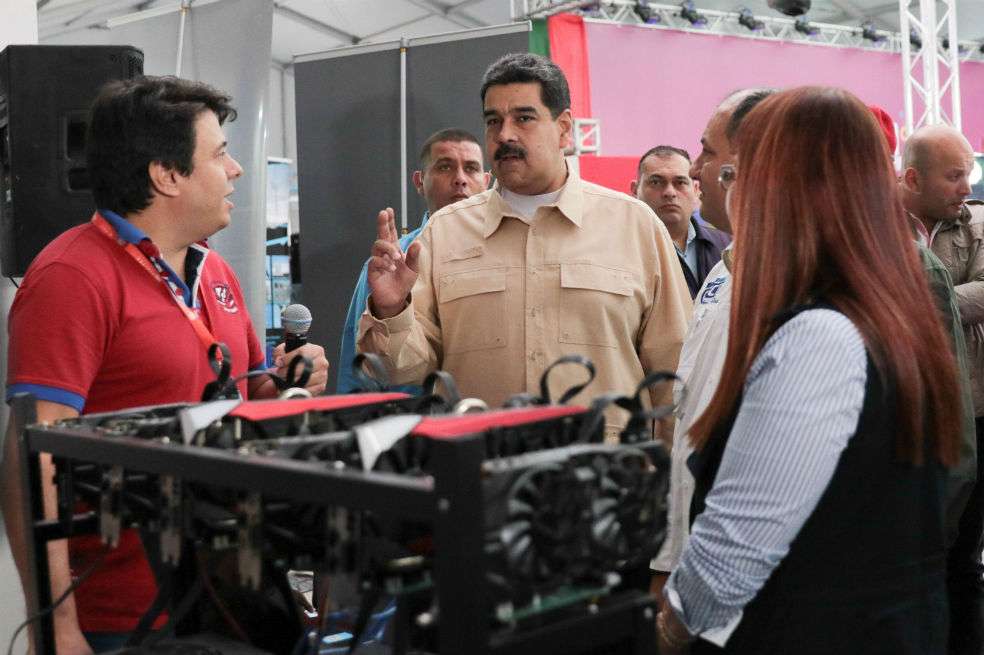 El presidente venezolano, Nicolás Maduro (C), habla frente a una computadora utilizada para extraer moneda cifrada. / AFP