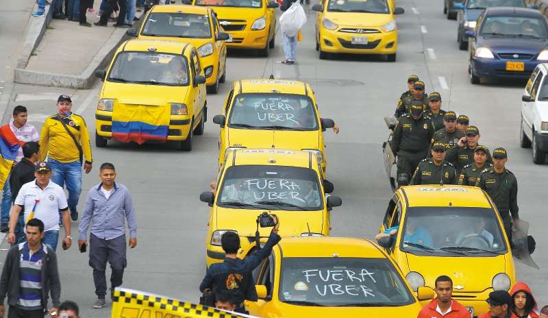 Taxi drivers march as they strike to pressure the government to ban the ride-sharing app Uber, in Bogota, Colombia, Wednesday, May 10, 2017. Hundreds of taxi drivers from different cities in Colombia began a strike on Wednesday, denouncing Uber as a "pirate" taxi service that does not meet the requirements required by law. (AP Photo/Fernando Vergara)