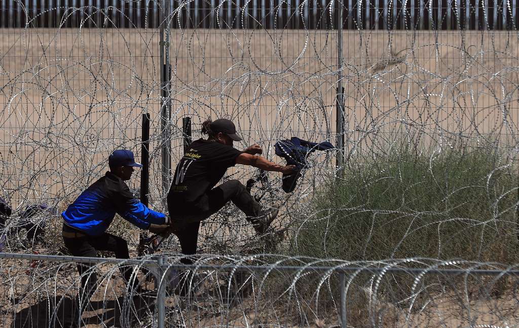 -FOTODELDÍA- MEX6524. CIUDAD JUÁREZ (MÉXICO), 03/05/2024.- Migrantes intentan cruzar por una barricada de alambre con púas en las inmediaciones de la frontera con Estados Unidos, el 2 de mayo de 2024, en Ciudad Juárez, estado de Chihuahua (México). Días después del anuncio de los presidentes de Estados Unidos, Joe Biden, y de México, Andrés Manuel López Obrador, de mayores acciones contra la migración, activistas e indocumentados varados en la frontera común advierten este viernes de crecientes riesgos, como secuestros a manos de traficantes y muertes en las rutas más peligrosas. EFE/Luis Torres
