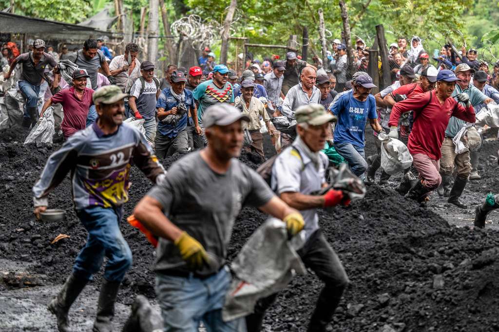 Emerald seekers run after entering 'La Voladora,' a cage where the multinational Esmeraldas Mining Services (EMS) leaves tons of soil discarded from its production, to search for green gems at the Las Animas River in Muzo, Boyaca Department, Colombia, on June 19, 2024.