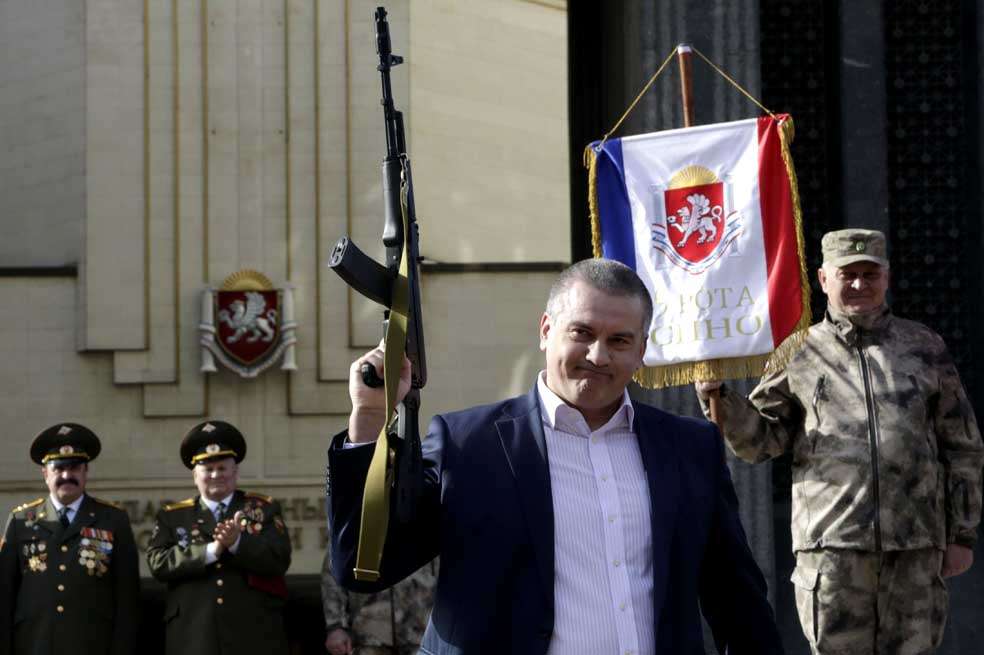El líder ruso de Crimea, Sergei Aksyonov sostiene un rifle automático AK47 durante la celebración del Día de los Defensores de la Patria, que se celebró en Crimea el 25 de febrero. / AFP