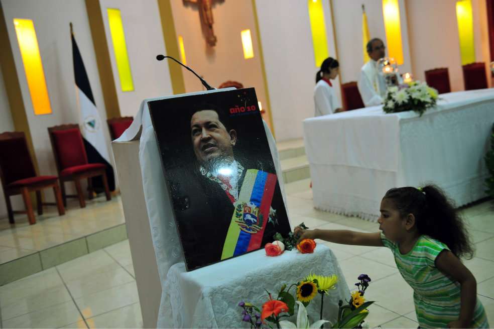 Las plegaras por Chávez se extienden por varios países. Una niña pone flores a su fotografía en Managua (Nicaragua). / AFP