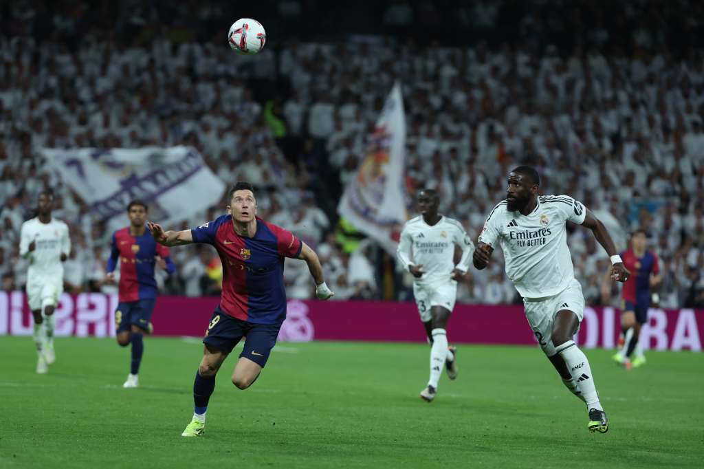 MADRID, 26/10/2024.- El defensa del Real Madrid Antonio Rudiger (d) persigue el balón con Robert Lewandowski, del FC Barcelona, durante el partido de la jornada 11 de LaLiga EA Sports entre el Real Madrid y el FC Barcelona, este sábado en el estadio Santiago Bernabéu, en Madrid. EFE/Kiko Huesca