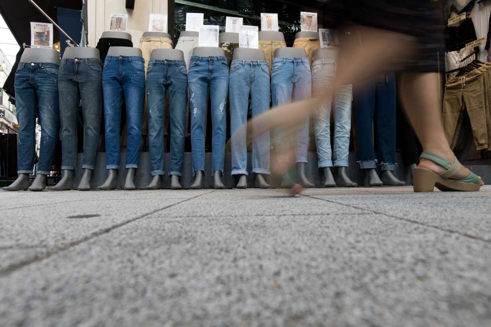 Una persona camina en frente de una vitrina con maniquíes con jeans.