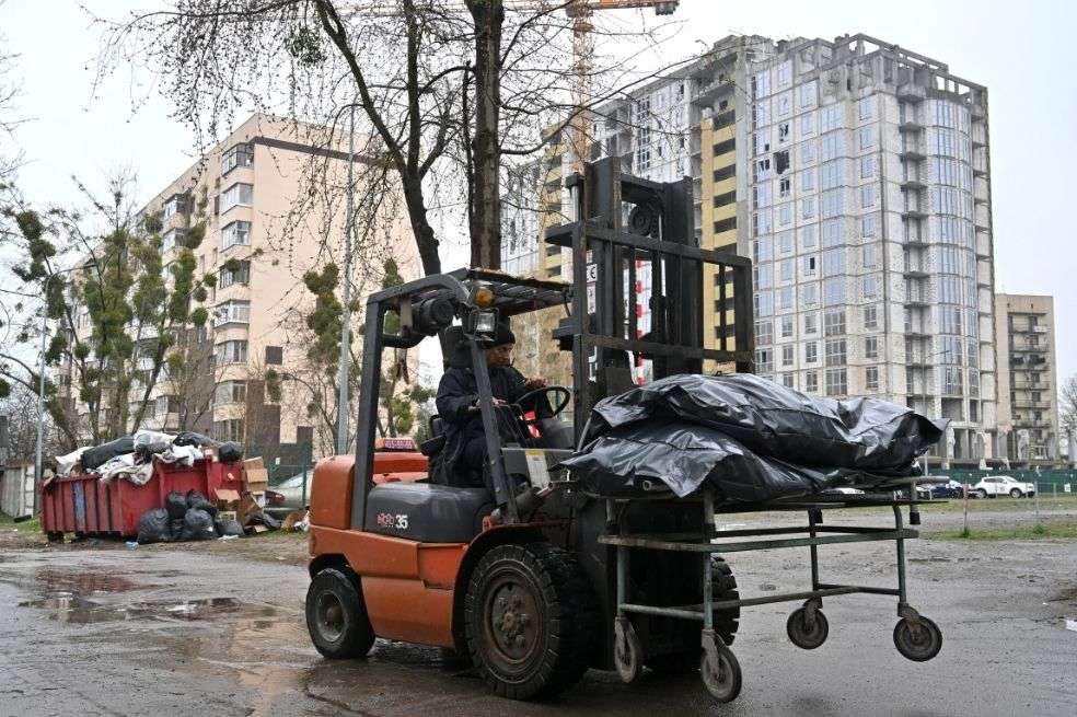 Un hombre conduce una carretilla con cuerpos exhumados para llevarlos a la morgue en Bucha, al noroeste de Kiev.