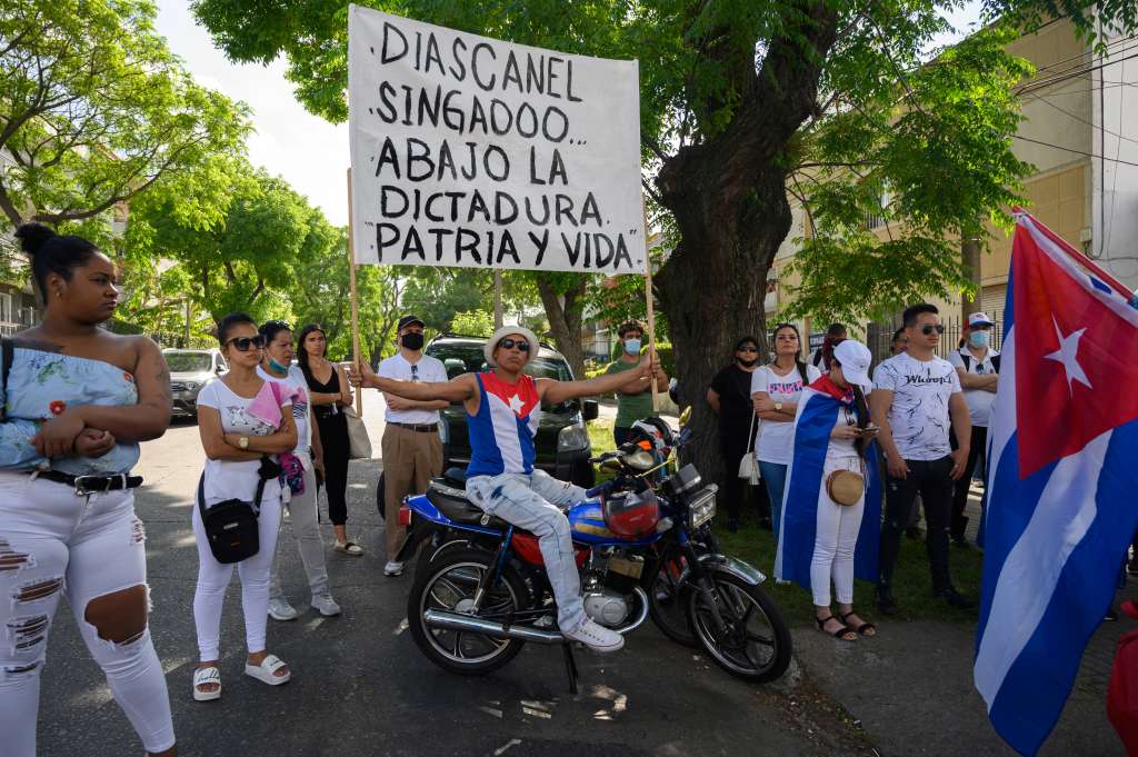 A group of Cubans living in Uruguay demonstrate in support of the Cuban opposition, in front of Cuba's embassy in Montevideo on November 15, 2021. - The Cuban opposition has said it will take to the streets as planned on Monday to demand the release of political prisoners, despite authorities banning the demonstration and preventing its organizers leaving their homes the day before. News of the "15N" (November 15) gathering in Havana and six provinces has spread rapidly on Cuban social media platforms in past weeks, with opposition supporters planning to highlight the continued detention of hundreds of prisoners jailed since history-making protests in July. (Photo by Pablo PORCIUNCULA / AFP)