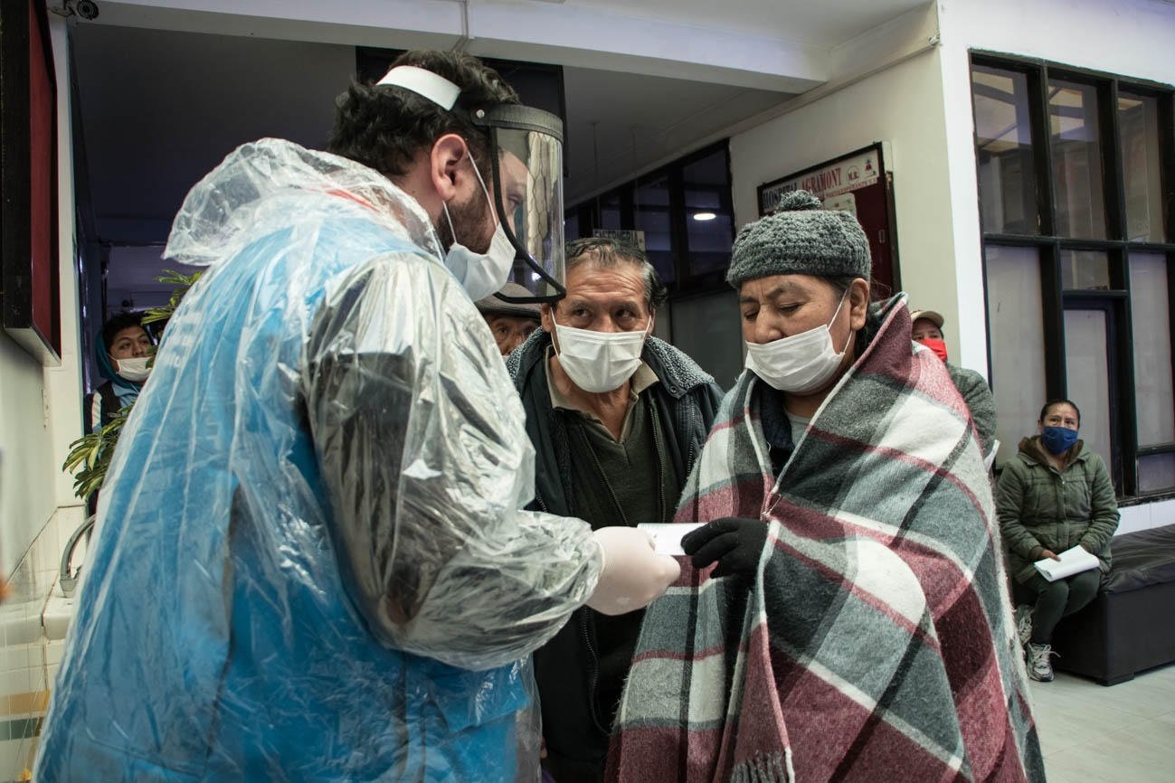 Fotografía cedida por el Programa Mundial de Alimentos (PMA) de uno de los miembros del PMA en Bolivia distribuyendo tarjetas de dinero electrónicas a personas en hemodiálisis para que puedan comprar alimentos durante la pandemia, en La Paz (Bolivia).