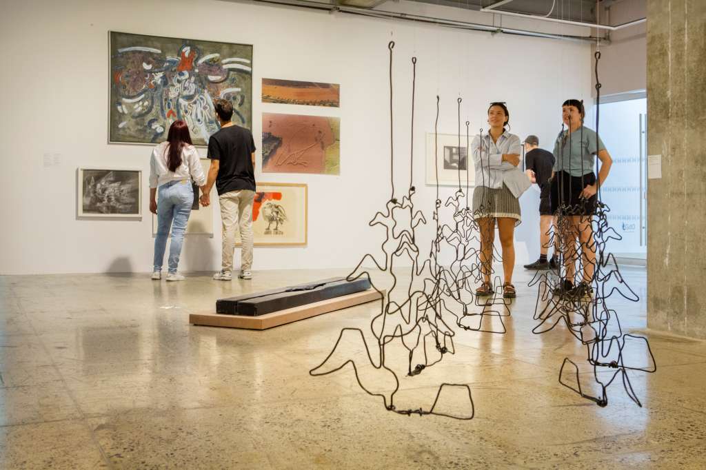 Visitantes observan algunas de las obras exhibidas en la exposición del Museo de la Tertulia.