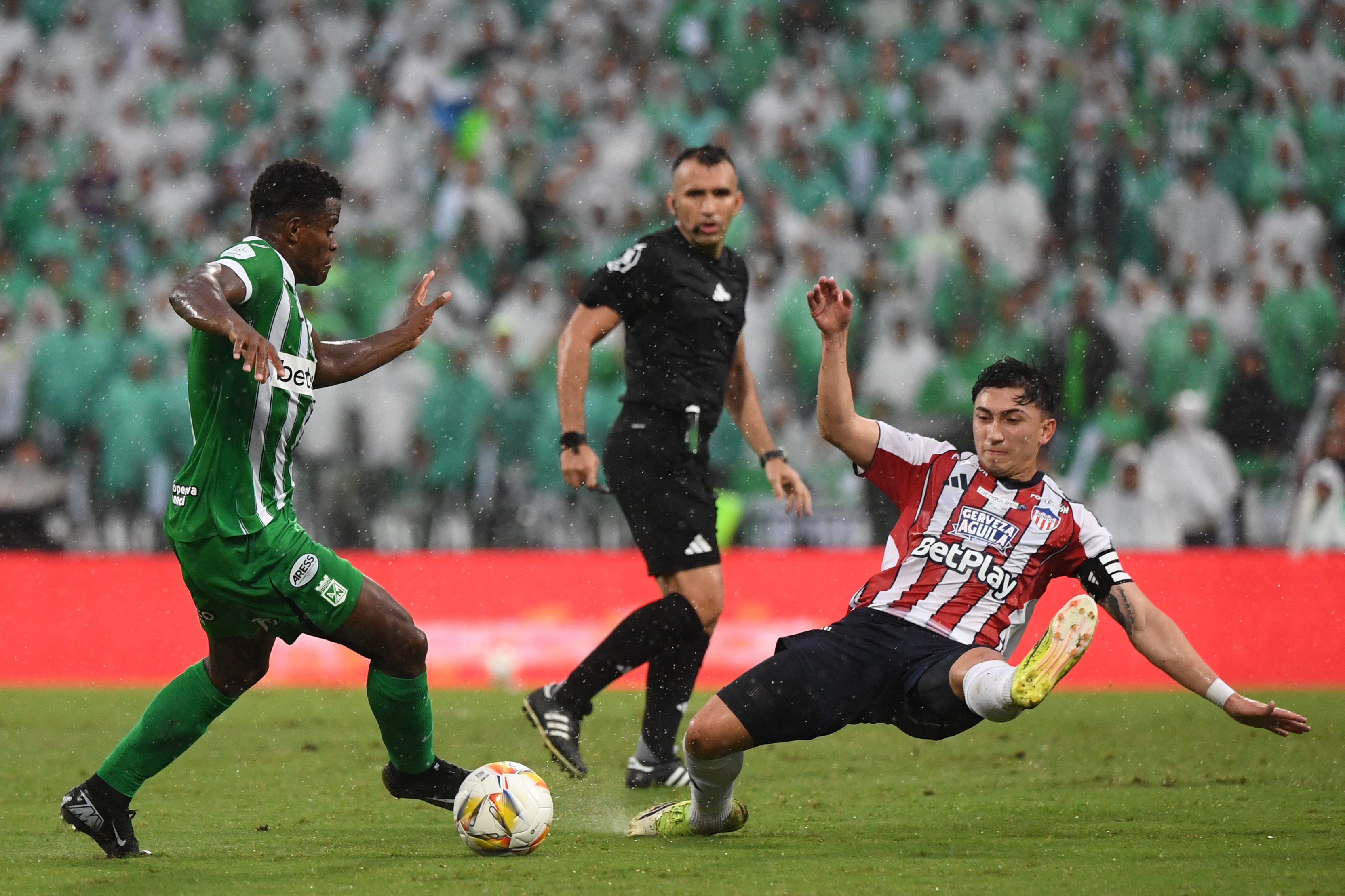 Atletico Nacional's defender #06 Andres Roman (L) and Junior's midfielder #80 Fabian Angel fight for the ball during the Colombian championship final second leg football match between Atletico Nacional and Junior at the Atanasio Girardot stadium in Medellin, Colombia on June 8, 2025. (Photo by Jaime SALDARRIAGA / AFP)