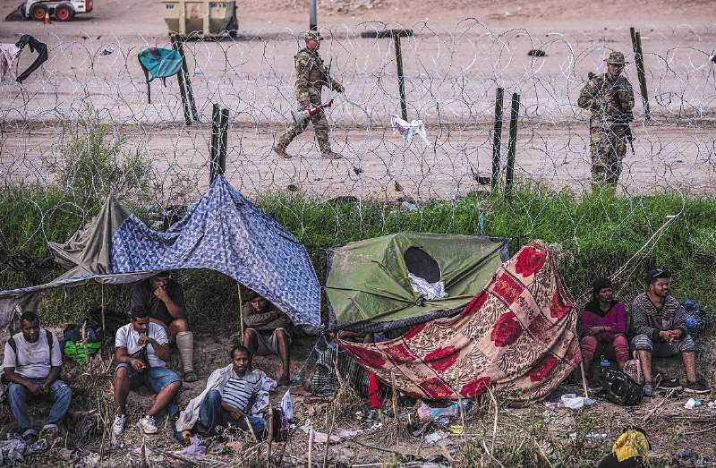 Migrantes se acercan a la barda que divide México de los Estados Unidos.