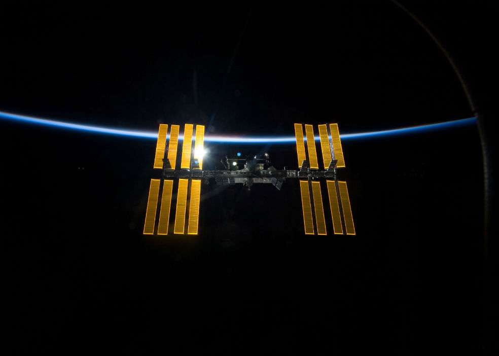 La Estación Espacial Internacional en contraste a la negrura del espacio y la delgada línea de la atmósfera de la Tierra. Imagen tomada desde el Transbordador Espacial Discovery antes de que las dos naves espaciales iniciasen su separación. / NASA