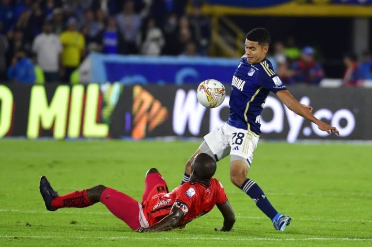 Stiven Vega, de Millonarios, disputa un balón con Luis Paz, de América.