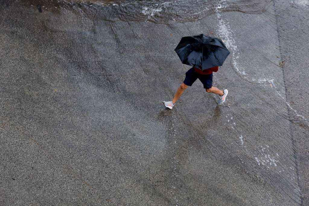 GRAFCVA1137. GODELLA (VALENCIA), 11/06/2024.- Una persona protegida con un paraguas cruza una calle cuando el cielo de la Comunitat Valenciana seguirá hoy nuboso y se esperan chubascos y tormentas ocasionales, que probablemente serán localmente fuertes en el interior y en el tercio sur la segunda mitad del día y no se descarta en el litoral central a primeras horas, según la Agencia Estatal de Meteorología. EFE/Kai Försterling