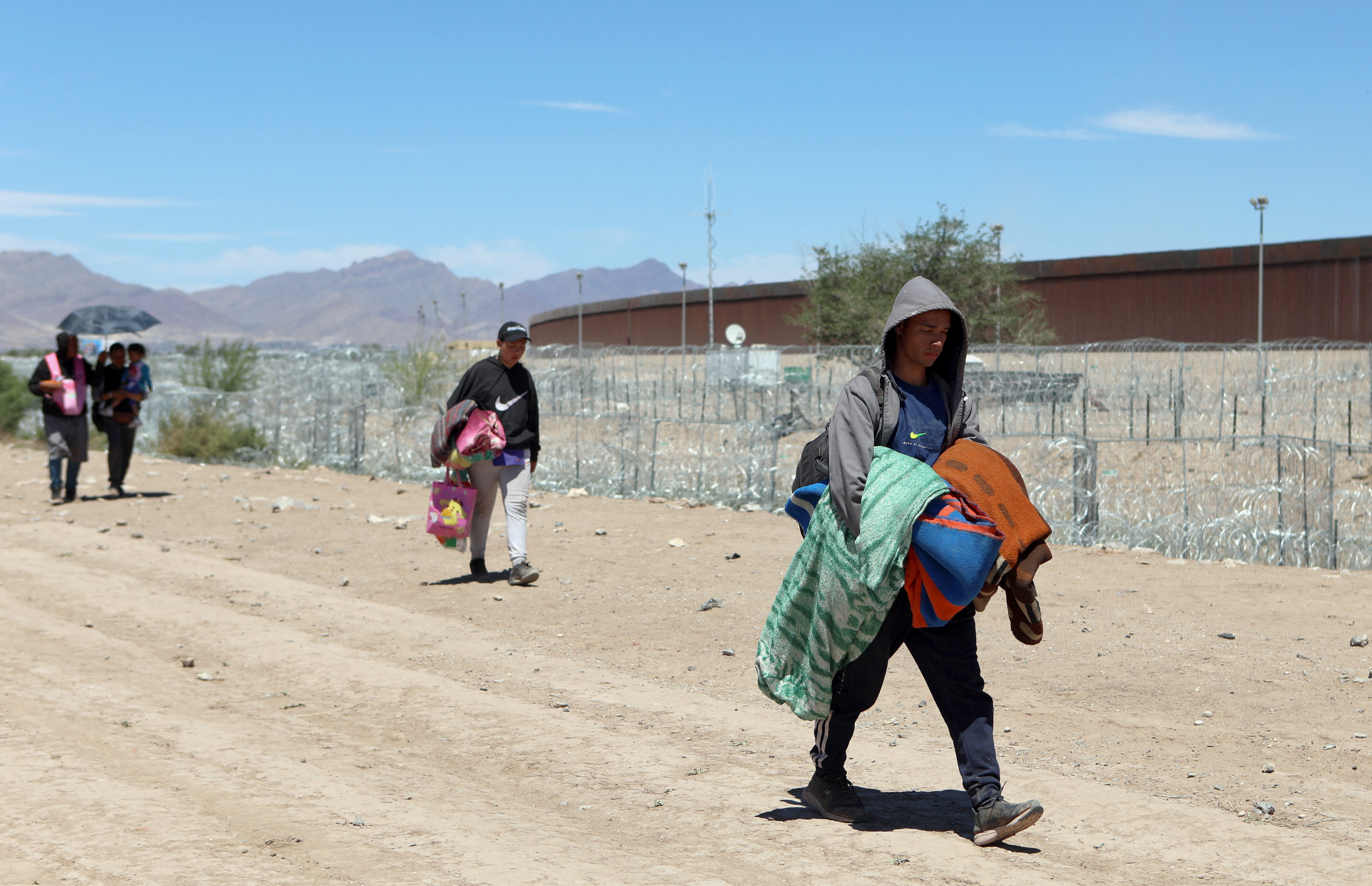 Migrants from Ecuador and Venezuela walk along the banks of the Rio Bravo in search of a gap to cross into the United States from Ciudad Juarez, Chihuahua state, Mexico, on April 18, 2024. (Photo by HERIKA MARTINEZ / AFP)