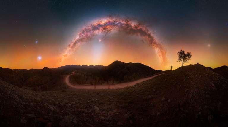 «Tomada desde el mirador de Razorback, en la cordillera de Flinders, en Australia Meridional, esta panorámica abarca todo el cielo nocturno del sur. La Vía Láctea se arquea sobre nuestras cabezas, mientras que las Nubes de Magallanes, la Grande y la Pequeña, se alzan al sur y la luz zodiacal surge por el este, todo ello visible en una sola noche de invierno. Esta imagen rinde homenaje a la extraordinaria claridad de los cielos oscuros de Australia, donde se pueden contemplar múltiples fenómenos celestes a la vez sobre un emblemático paisaje del interior».
