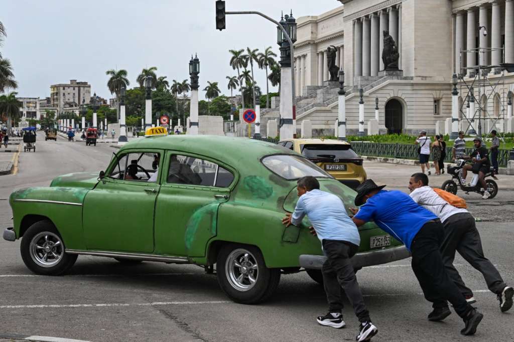 People push an old car along a street in Havana on July 29, 2026.