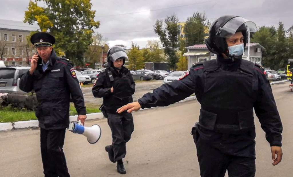Los oficiales de policía vigilan mientras los estudiantes evacuan un edificio del campus universitario de Perm