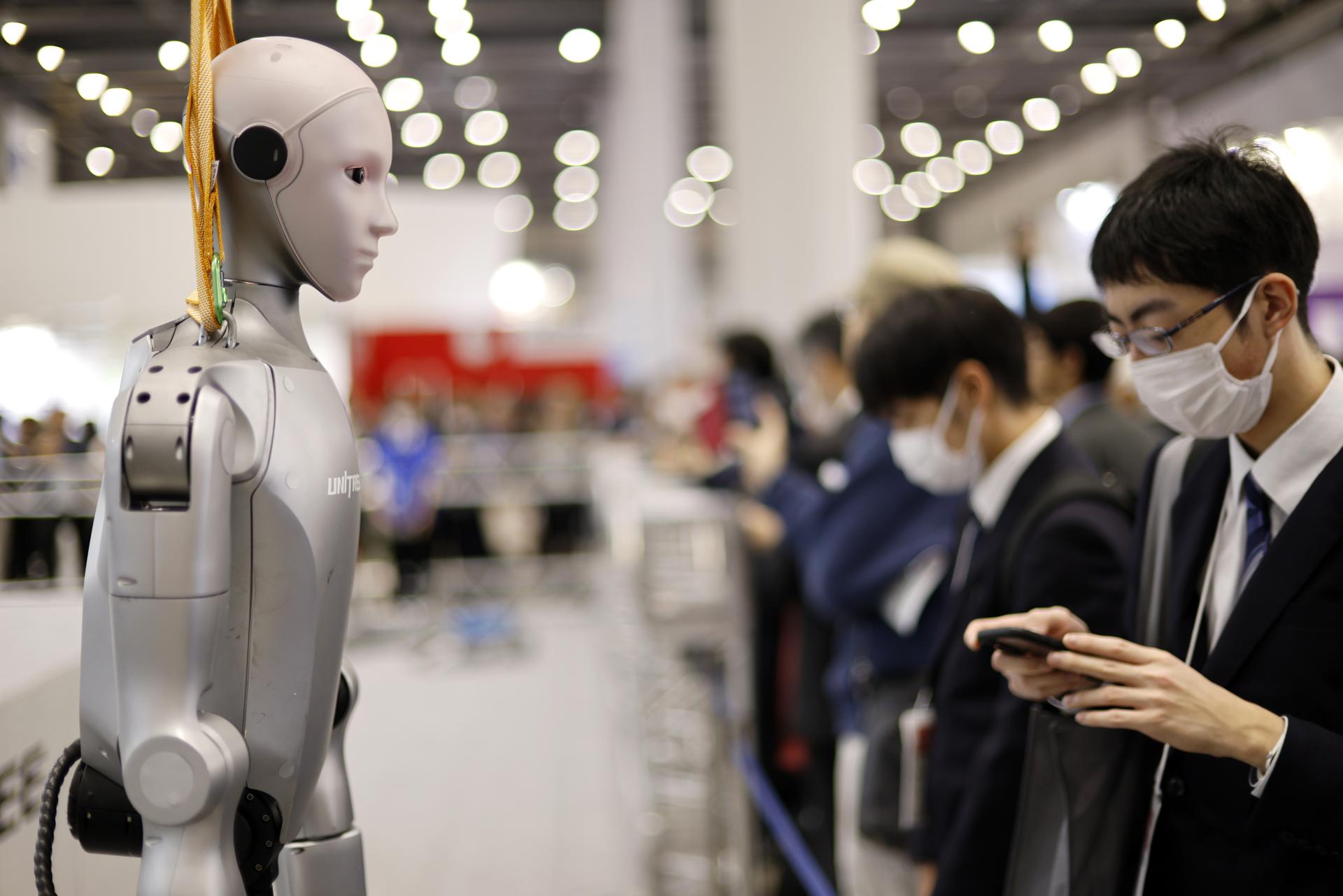 TOKYO (Japan), 03/12/2025.- A visitor stands next to a humanoid robot at the TechShare booth during the International Robot Exhibition 2025 (iREX2025) in Tokyo, Japan, 03 December 2025. Held once every two years, the iREX is one of the world’s largest robot trade shows. For the 2025 edition, 673 companies and organizations will be presenting their latest robot technologies until 06 December. (Japón, Tokio) EFE/EPA/FRANCK ROBICHON
