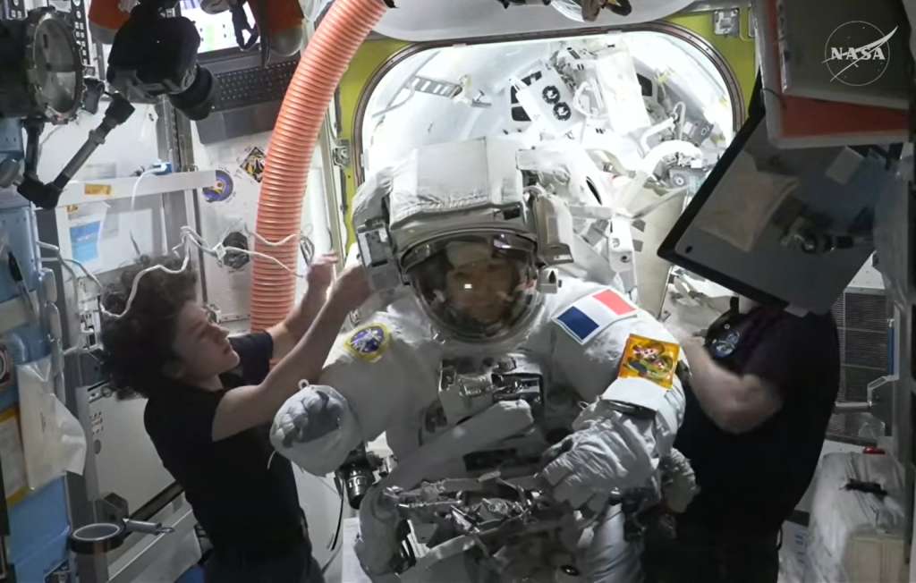 This August 18, 2026, frame grab from a NASA live video stream shows European Space Agency (ESA) French astronaut Sophie Adenot (C) returning back inside the International Space Station (ISS) after her spacewalk where she and NASA astronaut Anil Menon replaced a space-to-ground antenna on the orbital complex, according to NASA.