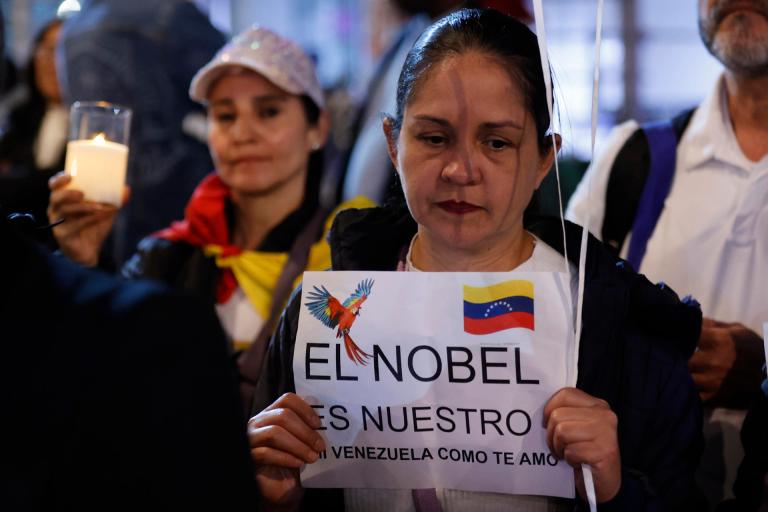 AME6464. BOGOTÁ (COLOMBIA), 06/12/2025.- Una mujer sostiene un cartel durante la marcha "por la paz y la libertad" en Venezuela, en conmemoración al Nobel de la Paz el 10 de diciembre a la líder antichavista María Corina Machado, este sábado, en Bogotá (Colombia). EFE/ Mauricio Dueñas Castañeda