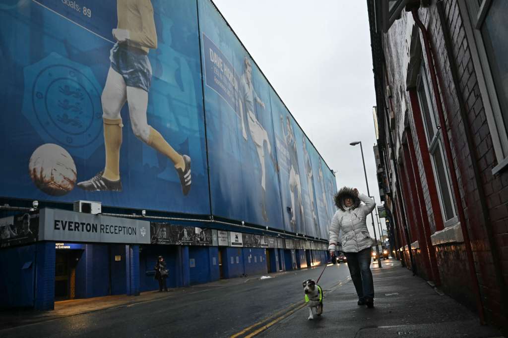 A dog-walker passes the ground as news of the postponement of the English Premier League football match between Everton and Liverpool spreads, outside Goodison Park in Liverpool, north west England on December 7, 2024.
