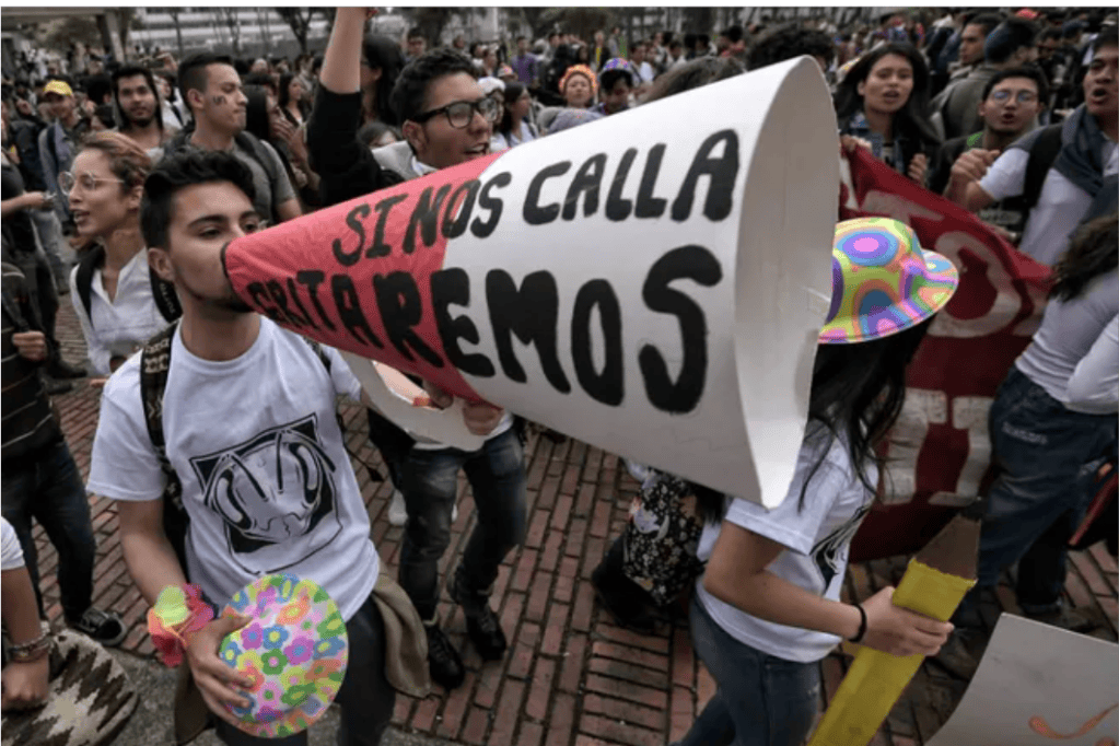 Jóvenes manifestándose en las calles. Uno de ellos tiene un cono con el que amplifica el mensaje: "si nos calla gritaremos".