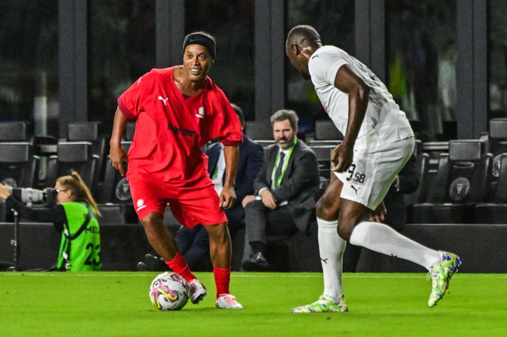 USA937. FORT LAUDERDALE (FL, EEUU), 05/12/2023.- El brasileño Ronaldinho (i) disputa el balón con el atleta jamaiquino Usain Bolt hoy, en el partido amistoso de Leyendas de la Conmebol disputado en el estadio DRV PNK en Fort Lauderdale (EE.UU.). La Conmebol celebró este martes un partido de leyendas en el que participaron, entre risas y abrazos, figuras como Ronaldinho, Carlos Valderrama e Iván Zamorano. EFE/ Giorgio Viera