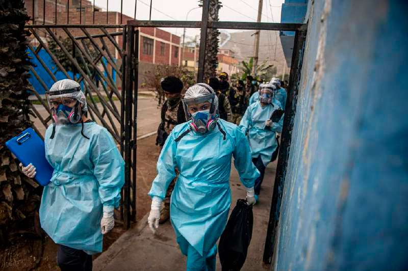Trabajadores del ministerio de Salud de Perú, escoltados por militares y policía, visitan barrios populares de Lima haciendo pruebas para COVID-19. / AFP