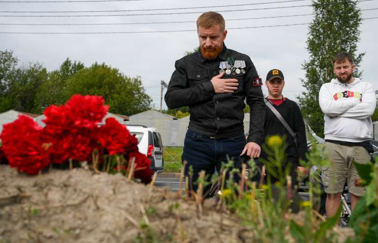 Personas trayendo flores al monumento improvisado.