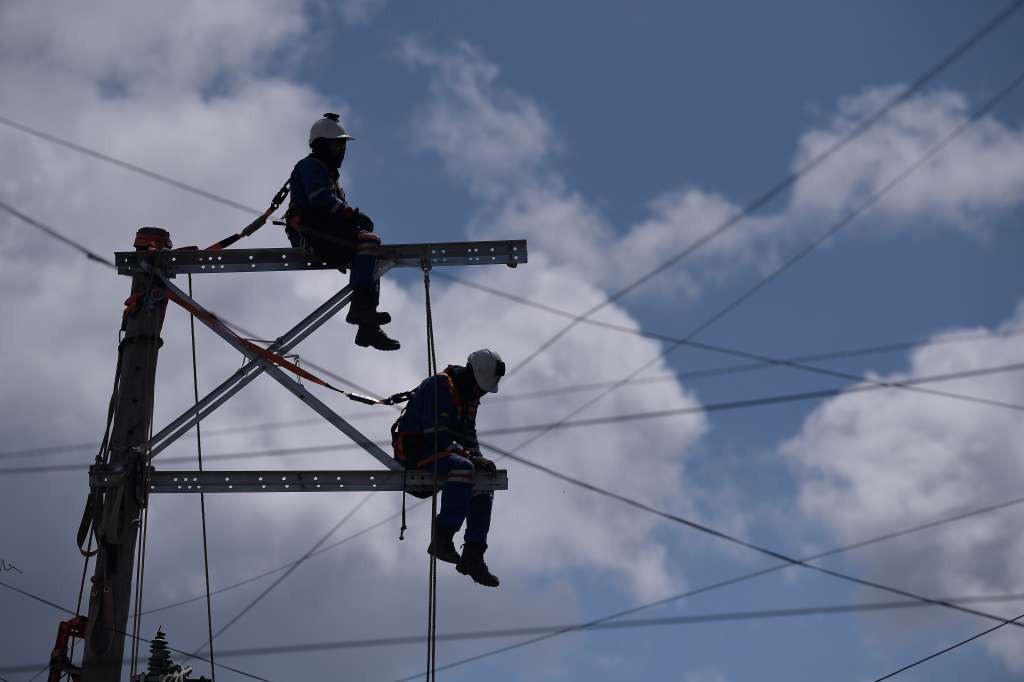 Hombres trabajando en un poste de energía eléctrica.