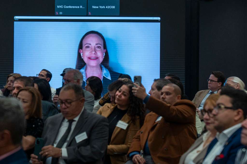 AME5956. NUEVA YORK (ESTADOS UNIDOS), 04/12/2025.- Personas observan a la líder opositora venezolana María Corina Machado (en pantalla) en una intervención virtual este jueves, durante un evento de la Asociación Venezolano-Estadounidense de EE.UU. (VAAUS) en Nueva York (Estados Unidos). EFE/ Angel Colmenares